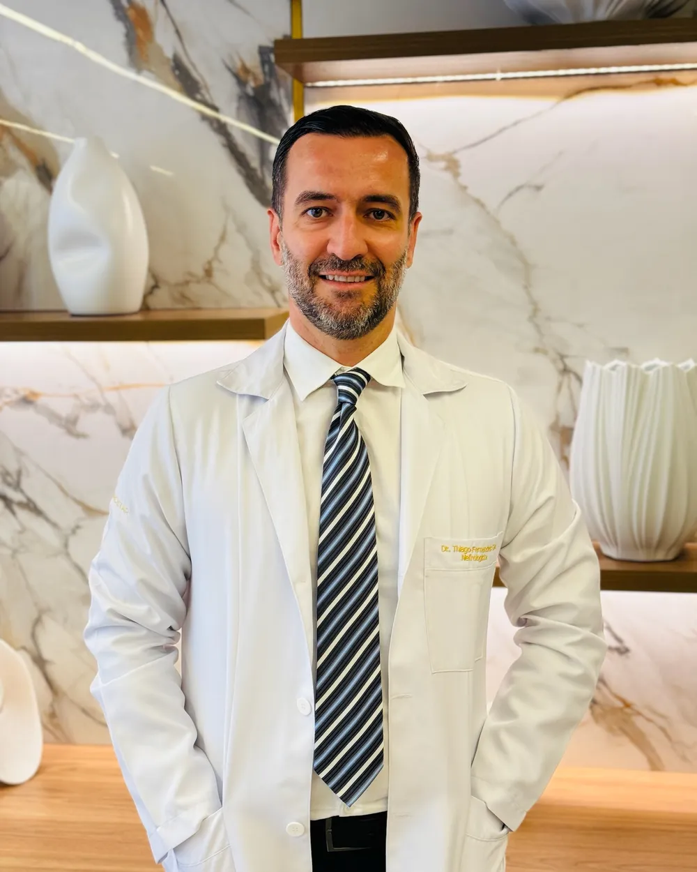 Dr. Thiago Diaz, médico nefrologista, de jaleco no consultório.